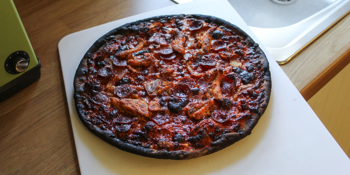 whole pizza pie with burnt crust and charred toppings