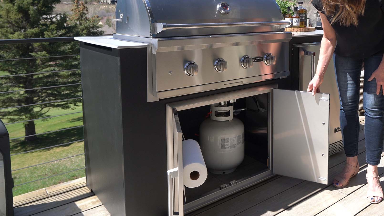 woman showing her propane tank in her outdoor kitchen