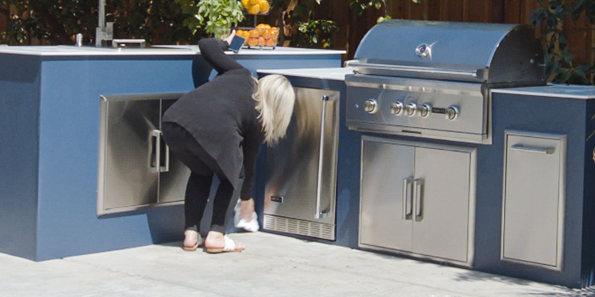 woman wiping down her coyote outdoor fridge
