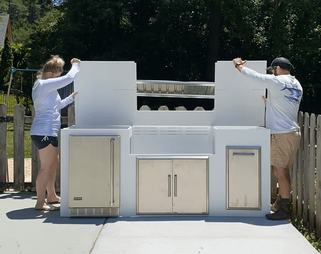 Two People Putting the Last Panel on Their MOKS Kitchen Before Adding the Grill