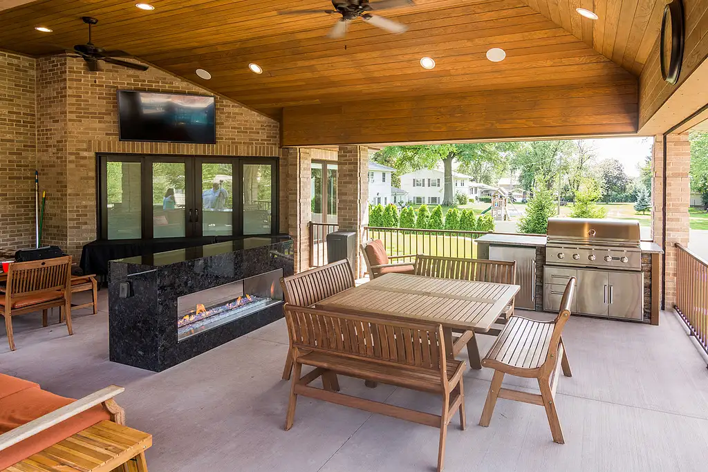 linear outdoor kitchen lounge space under covered area with outdoor tv and fireplace
